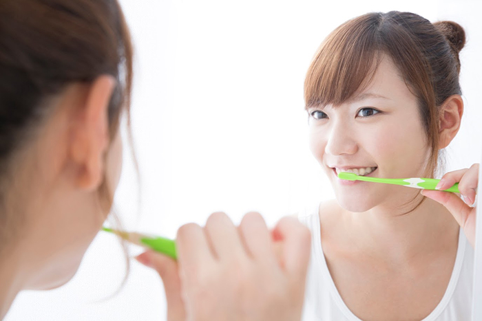 鏡の前で歯磨きをする女性